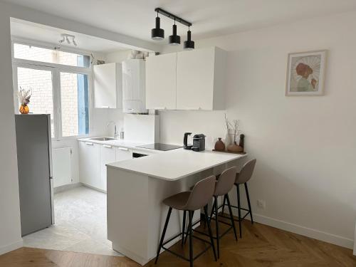 a white kitchen with a counter and stools in it at Appartement central niché en centre-ville in Saint-Germain-en-Laye