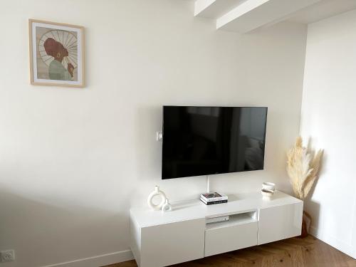 a white entertainment center with a flat screen tv on a wall at Appartement central niché en centre-ville in Saint-Germain-en-Laye