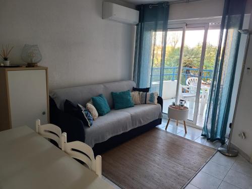 salon z kanapą i balkonem w obiekcie T2 climatisé à 5 minutes à pied de la plage avec parking, piscine et wifi w Fréjus