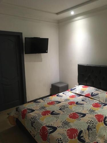 a bedroom with a bed with a floral comforter and a television at Pablo´s House in Guayaquil