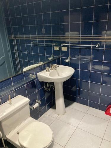 a blue tiled bathroom with a toilet and a sink at Pablo´s House in Guayaquil