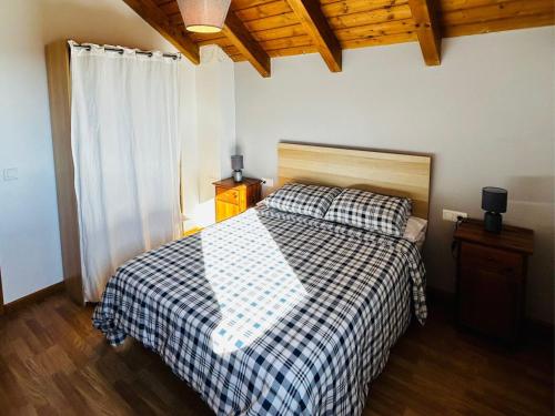 1 dormitorio con 1 cama con manta a cuadros en Casa Mya. A Modern Duplex in the Spanish Pyrenees, en Aso de Sobremonte