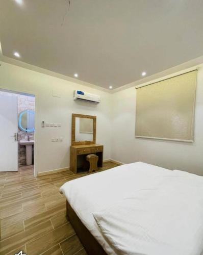 een slaapkamer met een wit bed en een spiegel bij شاليهات الود in Abha