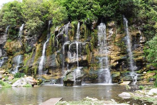 a waterfall in front of a mountain with a pond at Casa V.Giardino pileta y cochera in Villa Giardino