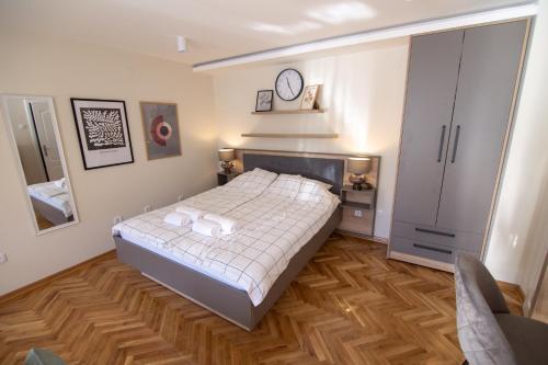 a bedroom with a bed and a clock on the wall at Apartmani Aleksandar in Vršac