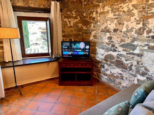 a living room with a tv and a stone wall at El Bulín de Patones in Patones