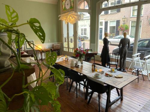 due donne in piedi in una stanza con un tavolo con fiori di B&B Het Atelier a Doesburg