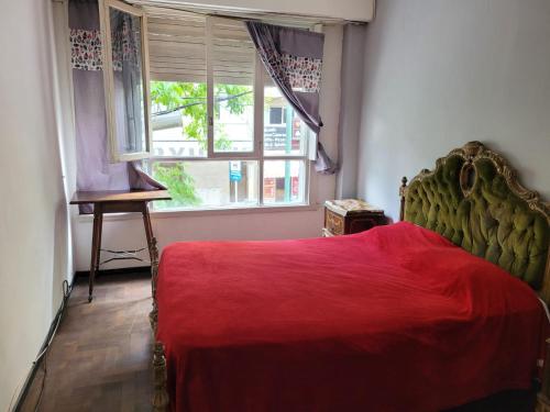 1 dormitorio con 1 cama con manta roja y ventana en Depto. 3 AMBIENTES con balcón a la calle 2 cuadras de la playa en Mar del Plata