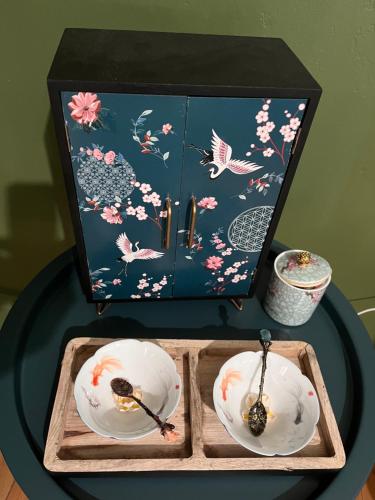 une table avec deux plaques et une boîte avec des oiseaux dans l'établissement Vers le soleil levant, à Croisilles
