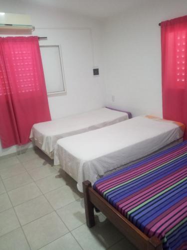 duas camas num quarto com cortinas vermelhas em monoambiente em Jesús María