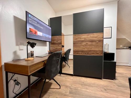 biuro z biurkiem i telewizorem na ścianie w obiekcie PrimeTime Suite für 2 mit Küche w Essen