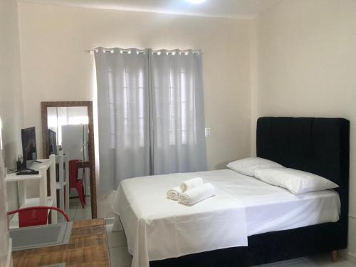 1 dormitorio con 1 cama con sábanas blancas y espejo en Comodidade e simplicidades a 240m do mar, en Florianópolis