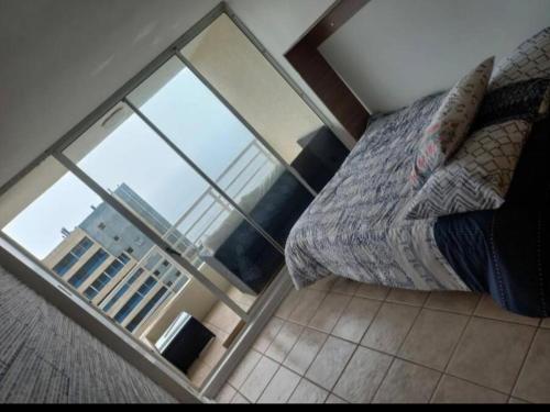 een slaapkamer met een bed en een groot glazen raam bij Reñaca departamento in Viña del Mar