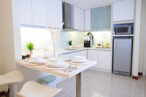a white kitchen with a table with dishes on it at 7 PAX, 1BR, 3mins to KLCC (3A05) in Kuala Lumpur