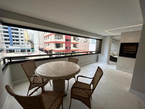 a room with a table and chairs and a large window at Apartamento Balneário in Balneário Camboriú