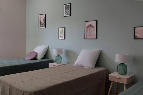 a bedroom with two beds and two lamps on tables at Gîte chaleureux le Petit Mauze in Nouaillé-Maupertuis