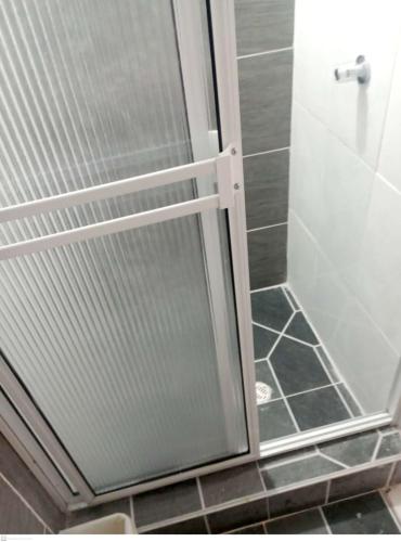 La salle de bains est pourvue d'une douche avec une porte en verre. dans l'établissement Habitación Privada, Br. El Nogal Armenia Quindío, Colombia, à Armenia