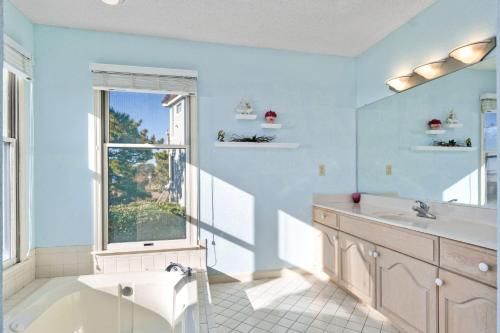 Baño azul con lavabo y ventana en B20 Bay Meadow 20, en Nags Head