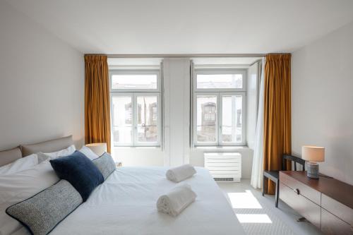 a bedroom with a white bed and two windows at L'Olivier 23 - 2 apartments in a recently renovated Guesthouse in Porto