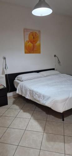- une chambre dotée d'un lit blanc avec une photo sur le mur dans l'établissement Bilocale via Rimini 5C, à Pomezia