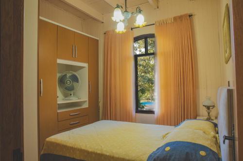 a bedroom with a bed with orange curtains and a window at Sítio Vale dos Vinhedos in Bento Gonçalves