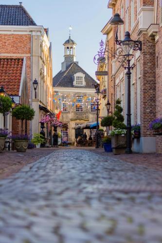 a cobblestone street in a town with a clock tower at De Bakkerij in Deurningen