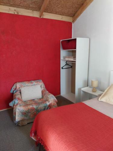 a bedroom with a red wall and a bed and a chair at Cabañas el Rombo in Puerto Montt