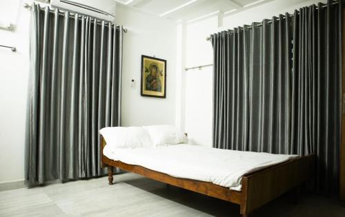 a bed in a room with black and white curtains at Urban Oasis Homestay: AC Bedrooms in Trichūr