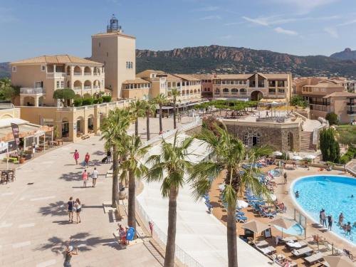 - une vue sur un complexe avec des palmiers et une piscine dans l'établissement Appartement 2 pièces avec terrasse et vue mer, accès piscine et parking inclus - FR-1-504-677, à Saint-Raphaël