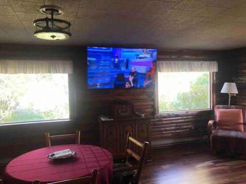a dining room with a table and a tv on the wall at The Huron Hutch in Evergreen Shores