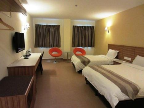 a hotel room with two beds and a desk and two chairs at Grand Court Hotel in Teluk Intan