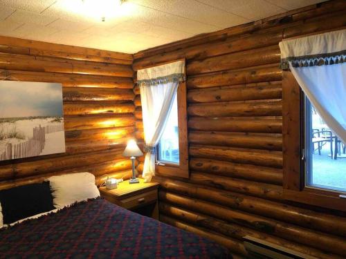 a bedroom with wooden walls and a bed and a window at The Huron Hutch in Evergreen Shores