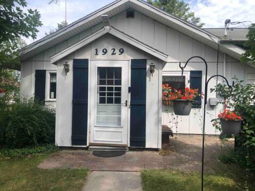 a white house with a blue door and flowers at The Huron Hutch in Evergreen Shores