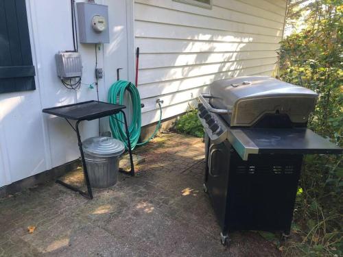 a grill and a table next to a house at The Huron Hutch in Evergreen Shores