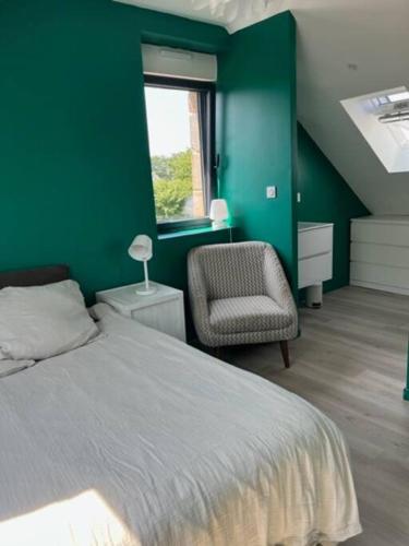 ein grünes Schlafzimmer mit einem Bett und einem Stuhl in der Unterkunft Maison en Baie du Mont St Michel in Le Val-Saint-Père