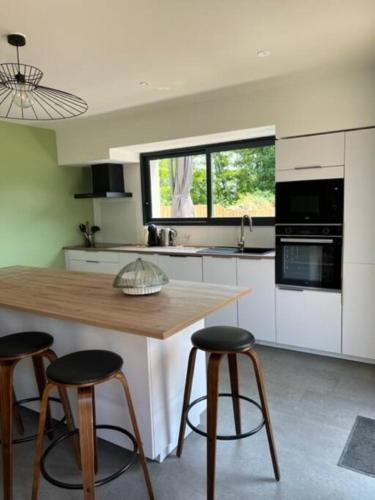 une cuisine avec une table en bois et deux tabourets dans l'établissement Maison en Baie du Mont St Michel, à Le Val-Saint-Père