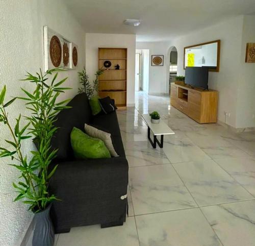 a living room with a black couch and a tv at La Casita de Bonnie in La Tejita