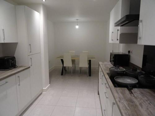 a kitchen with white cabinets and a table in it at Magnolia Palace/Group Long Stays in Killingbeck