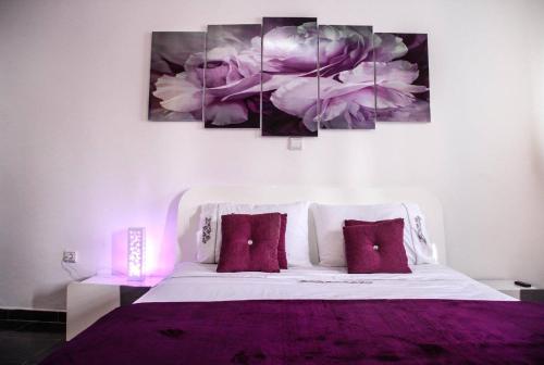 a bedroom with a purple bed with three paintings on the wall at sidi kaouki ayt karoum in Sidi Kaouki