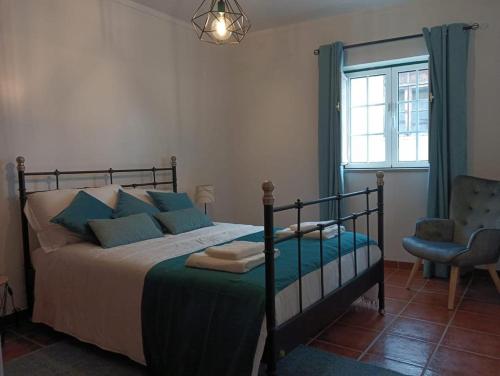 a bedroom with a bed and a chair and a window at Alojamentos Vila Alpalhão in Alpalhão