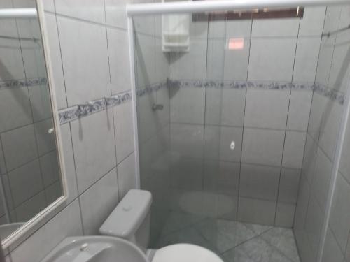 een witte badkamer met een toilet en een douche bij Apartamento em Cabo Frio com Wi-fi in Cabo Frio