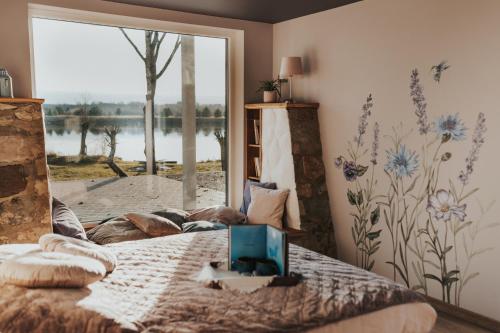 1 dormitorio con 1 cama y vistas al lago en Zilais Zirgs, en Skrīveri