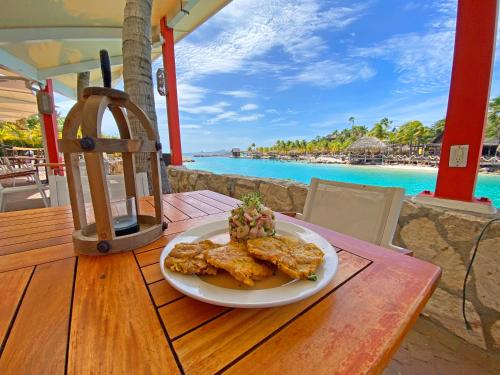 a plate of food on a table with a view of the ocean at The Royal Sea Aquarium Resort in Willemstad