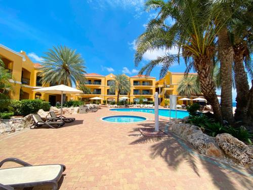 a resort with a swimming pool and palm trees at The Royal Sea Aquarium Resort in Willemstad