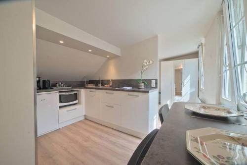 une cuisine avec des armoires blanches et un plancher en bois dans l'établissement Le studio de la république - 2P - Hyper centre Metz, à Metz