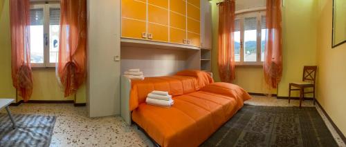 Una cama naranja en una habitación con toallas. en AL CAMPANILE centro storico ampio luminoso e panoramico appartamento trilocale en Carsoli