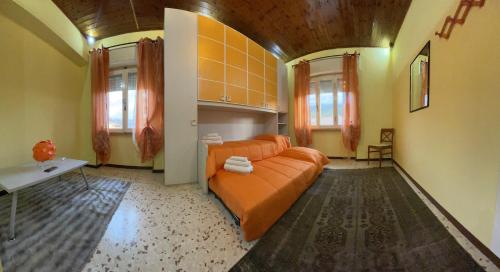 un soggiorno con divano arancione e 2 finestre di AL CAMPANILE centro storico ampio luminoso e panoramico appartamento trilocale a Carsoli