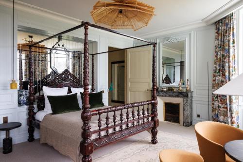 Domaine de Locguénolé & Spa - Relais & Chateaux في Kervignac: غرفة نوم مع سرير المظلة ومدفأة