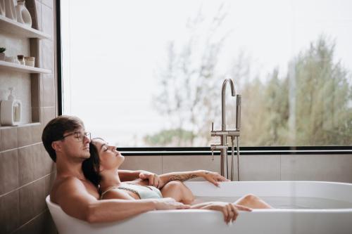 a man and woman laying in a bath tub at O Chalé da Praia in Jaguaruna