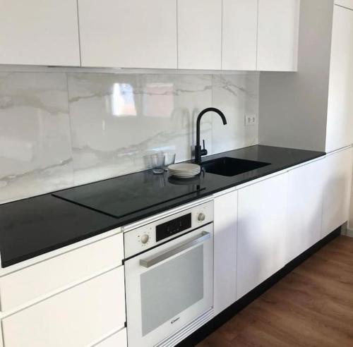 a white kitchen with a sink and a stove at Caparica Beach House in Costa da Caparica